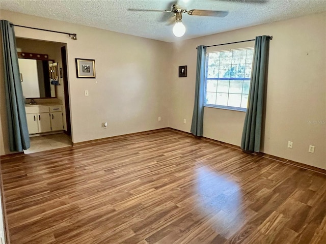 unfurnished bedroom featuring ceiling fan, light hardwood / wood-style flooring, a textured ceiling, and ensuite bath