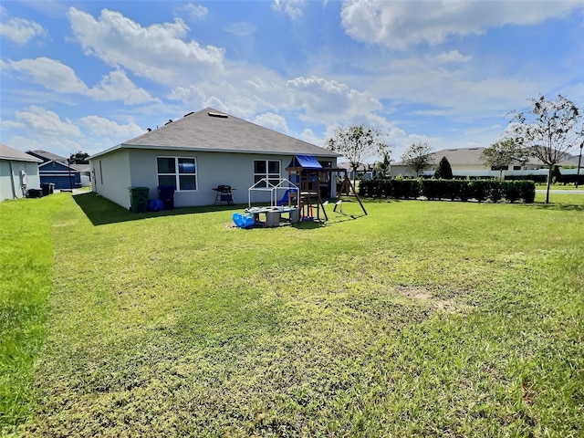 back of house featuring a playground and a yard