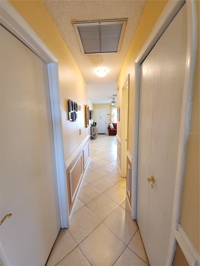 hallway featuring light tile patterned flooring and a textured ceiling