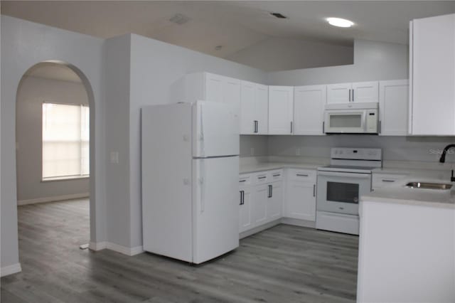 kitchen featuring white cabinetry, sink, vaulted ceiling, white appliances, and light wood-type flooring