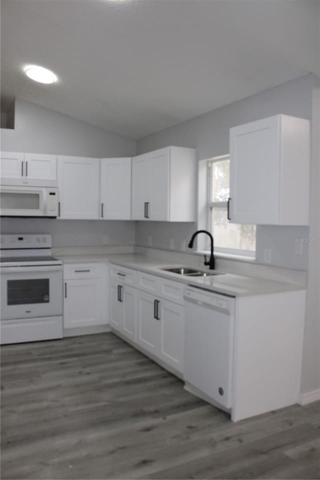 kitchen featuring white cabinetry, sink, dark wood-type flooring, vaulted ceiling, and white appliances