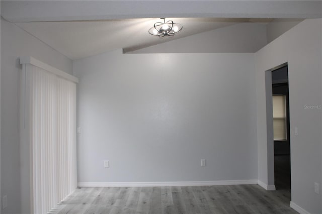 spare room featuring hardwood / wood-style floors and vaulted ceiling