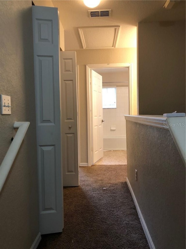 hall featuring carpet and a textured ceiling