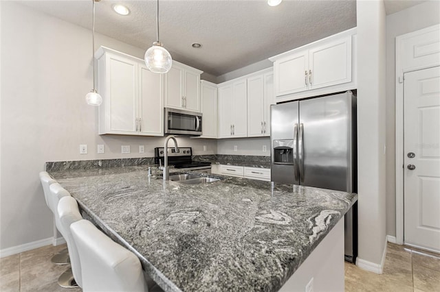 kitchen featuring appliances with stainless steel finishes, a breakfast bar, white cabinets, kitchen peninsula, and decorative light fixtures