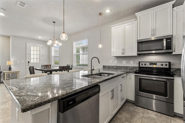 kitchen featuring white cabinets, stainless steel appliances, a textured ceiling, sink, and a notable chandelier