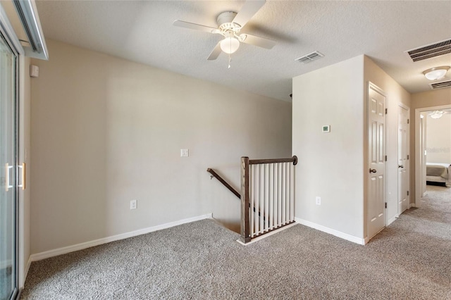 carpeted empty room with ceiling fan and a textured ceiling