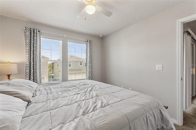 bedroom with ceiling fan, carpet floors, and a textured ceiling