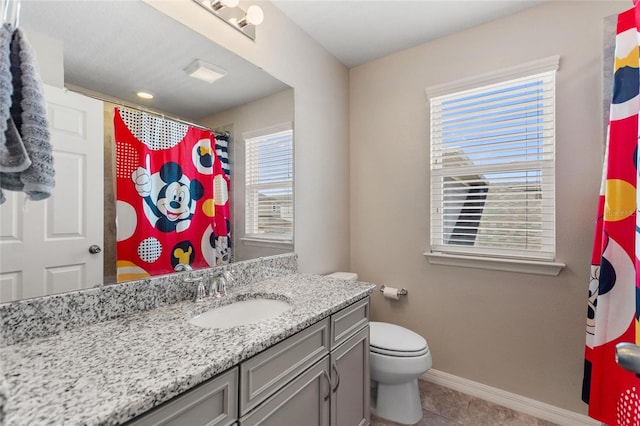 bathroom featuring vanity, tile patterned floors, toilet, and a wealth of natural light