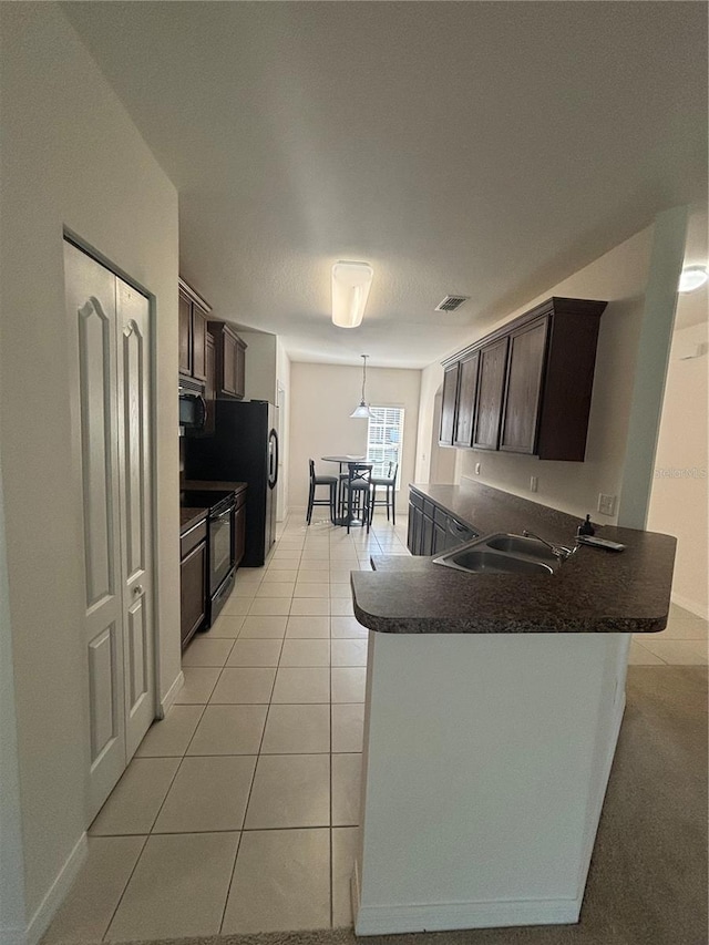 kitchen featuring black electric range oven, kitchen peninsula, dark brown cabinetry, and light tile patterned flooring