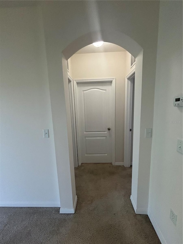 hallway featuring dark colored carpet