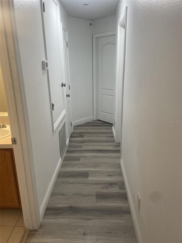 hallway with hardwood / wood-style flooring and sink