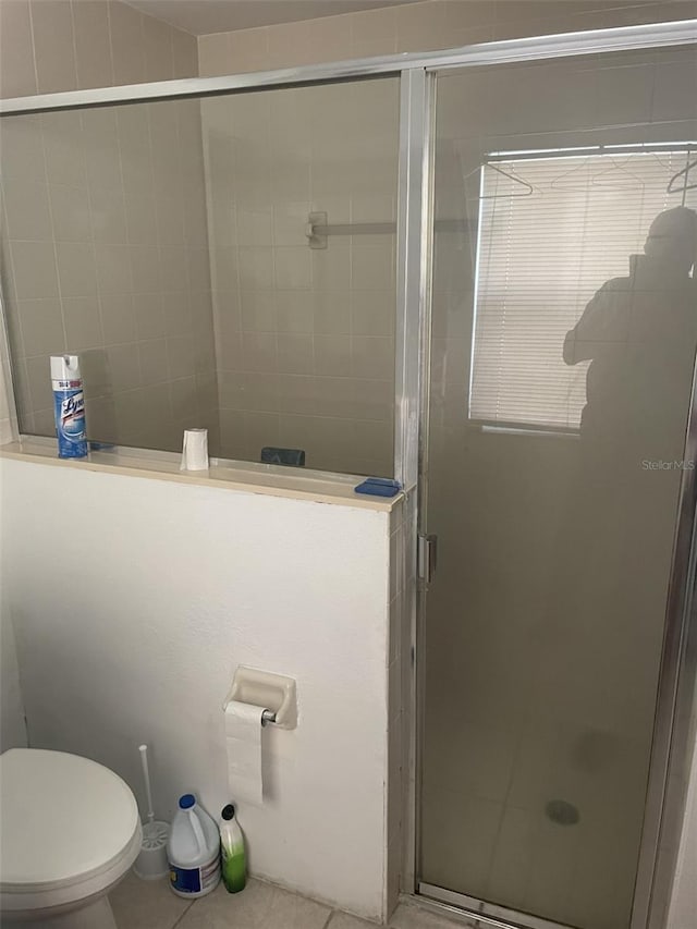 bathroom featuring toilet, tile patterned floors, and a shower with shower door