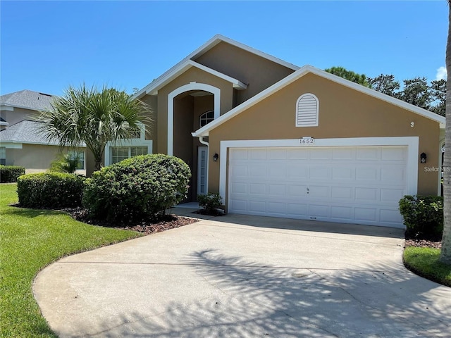 view of front facade with a garage, driveway, and stucco siding