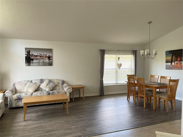 dining area with lofted ceiling, a textured ceiling, hardwood / wood-style flooring, and a notable chandelier