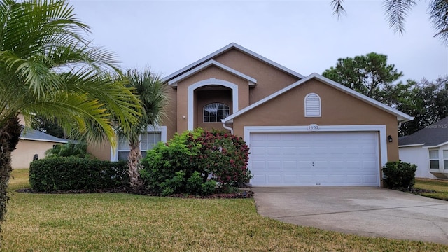 view of front of property featuring a garage, driveway, a front lawn, and stucco siding