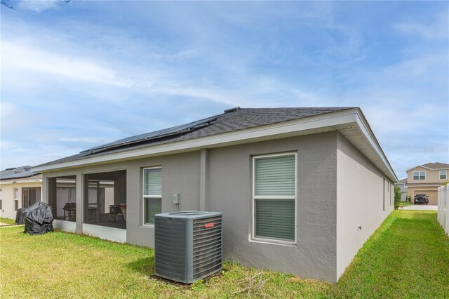 872 Sydney St, Davenport, FL 33837 - back of property featuring central AC, solar panels, stucco siding, a lawn, and a sunroom