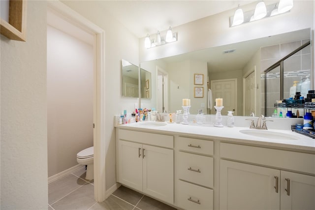 bathroom featuring toilet, vanity, tile patterned floors, and a shower with door