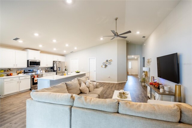 living room featuring high vaulted ceiling, ceiling fan, sink, and light hardwood / wood-style floors