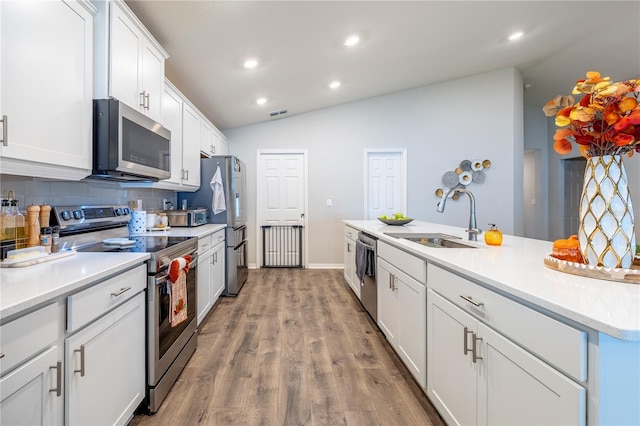 kitchen featuring light hardwood / wood-style floors, sink, appliances with stainless steel finishes, white cabinets, and vaulted ceiling