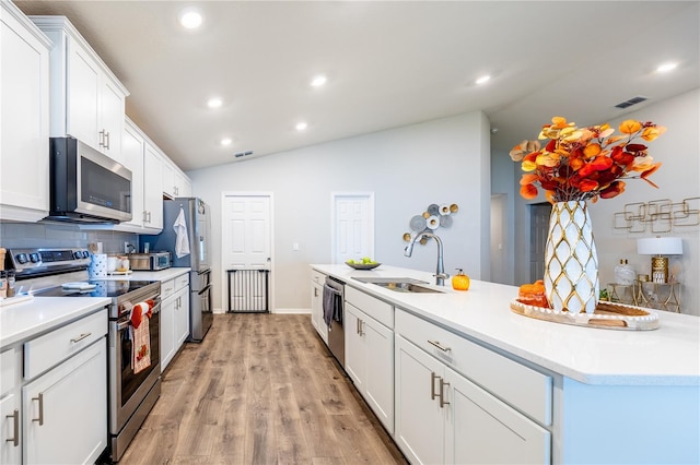 kitchen with white cabinetry, appliances with stainless steel finishes, sink, lofted ceiling, and light hardwood / wood-style flooring