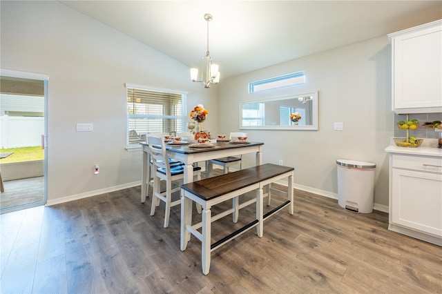 dining space featuring an inviting chandelier, vaulted ceiling, and dark hardwood / wood-style floors