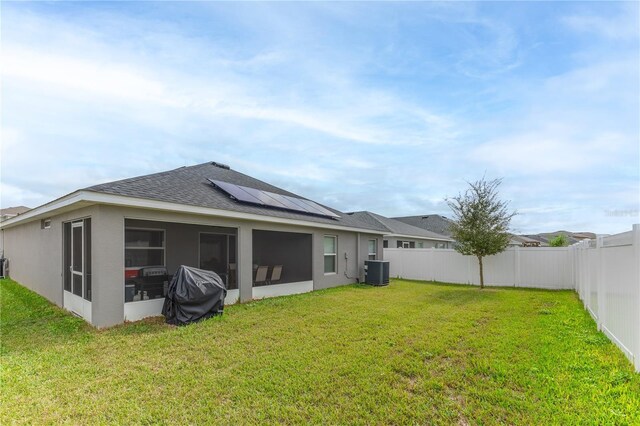 872 Sydney St, Davenport, FL 33837 - back of house featuring cooling unit, roof mounted solar panels, roof with shingles, a sunroom, and stucco siding