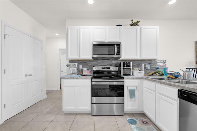 kitchen with appliances with stainless steel finishes, sink, tasteful backsplash, and white cabinetry