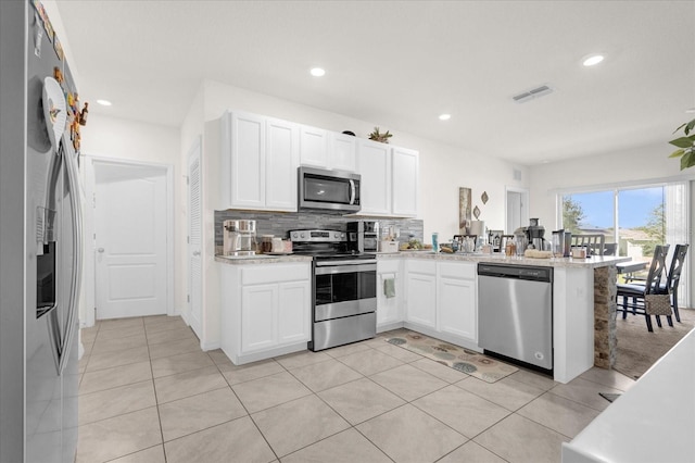 kitchen featuring light tile patterned flooring, stainless steel appliances, kitchen peninsula, and white cabinetry