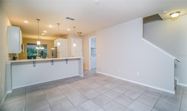 kitchen with white cabinets, pendant lighting, light tile patterned floors, kitchen peninsula, and a kitchen breakfast bar