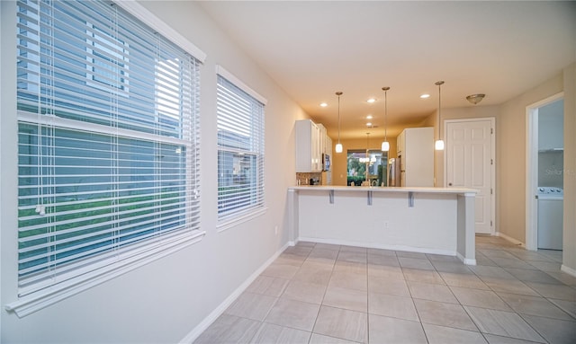 kitchen with a kitchen breakfast bar, white cabinets, kitchen peninsula, light tile patterned floors, and pendant lighting