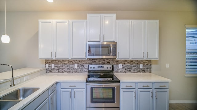 kitchen featuring white cabinets, hanging light fixtures, sink, backsplash, and appliances with stainless steel finishes