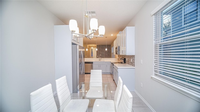 kitchen with stainless steel appliances, white cabinets, hanging light fixtures, and light tile patterned floors