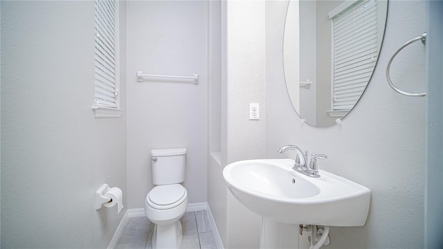 bathroom with toilet, sink, and tile patterned floors