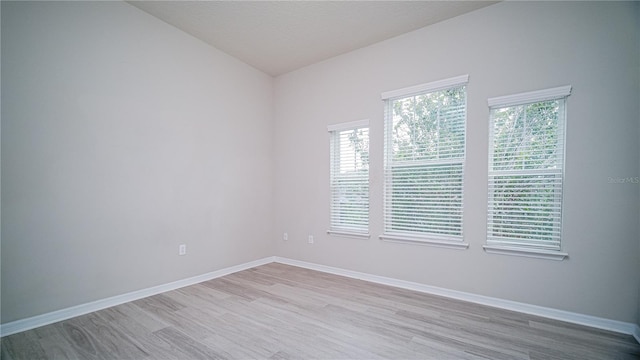 spare room with light wood-type flooring and lofted ceiling