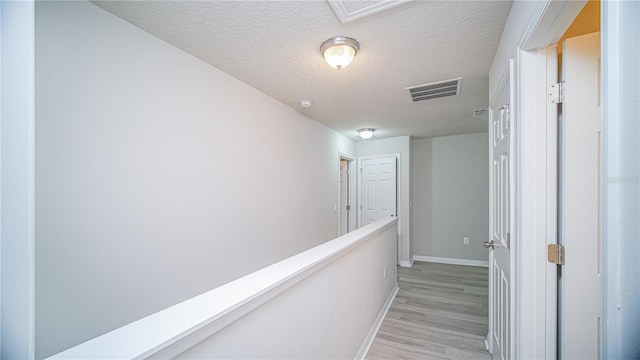 corridor featuring light hardwood / wood-style floors and a textured ceiling