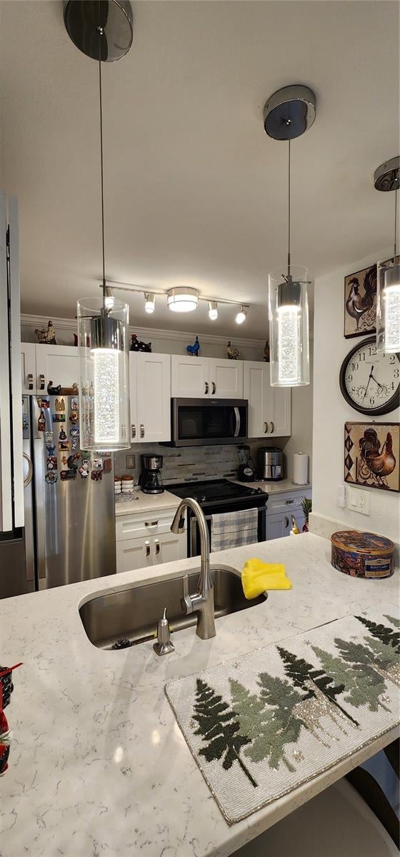 kitchen with light stone countertops, stainless steel appliances, white cabinets, and decorative light fixtures