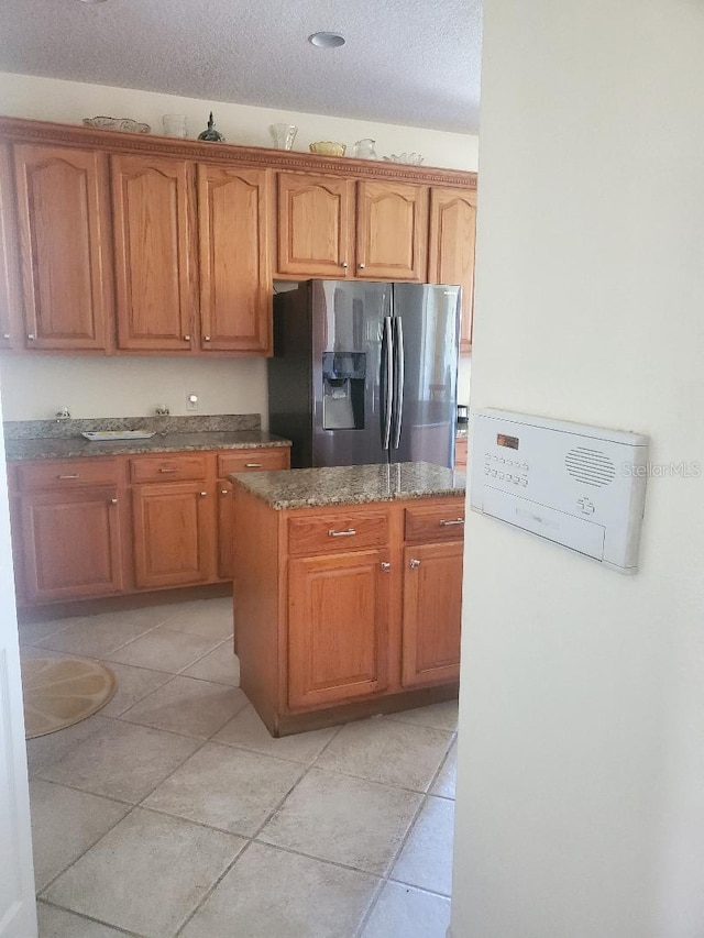 kitchen featuring stainless steel fridge, light tile patterned flooring, and a textured ceiling