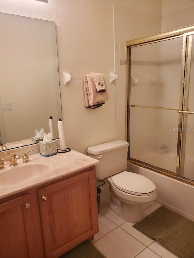 full bathroom featuring vanity, bath / shower combo with glass door, toilet, and tile patterned flooring