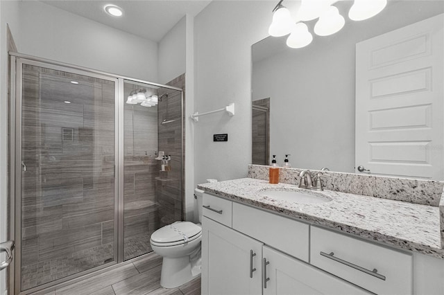 bathroom with vanity, hardwood / wood-style floors, toilet, and a shower with door