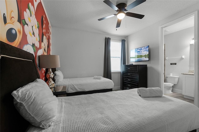 bedroom featuring ceiling fan, a textured ceiling, hardwood / wood-style floors, and ensuite bathroom