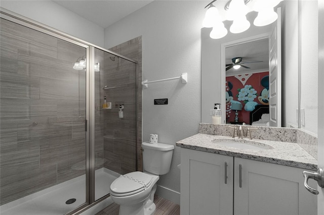 bathroom with ceiling fan, vanity, a shower with shower door, and toilet