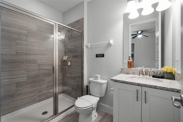 bathroom featuring wood-type flooring, a shower with shower door, ceiling fan, vanity, and toilet