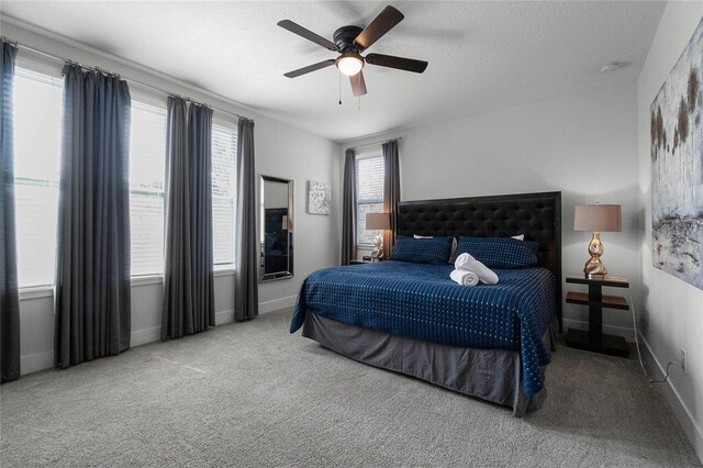 carpeted bedroom featuring ceiling fan and a textured ceiling