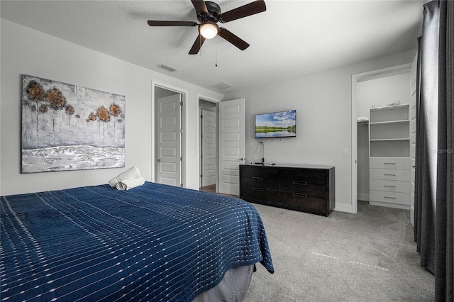 carpeted bedroom featuring a spacious closet, a closet, ceiling fan, and a textured ceiling