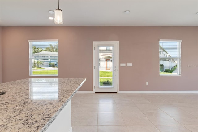 kitchen with light stone countertops, hanging light fixtures, and light tile patterned flooring