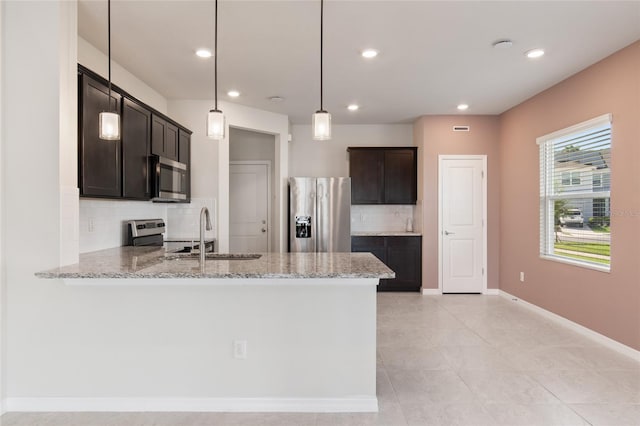 kitchen featuring light stone counters, pendant lighting, stainless steel appliances, and sink