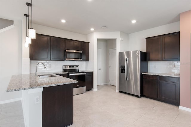 kitchen featuring dark brown cabinetry, pendant lighting, light stone counters, sink, and appliances with stainless steel finishes