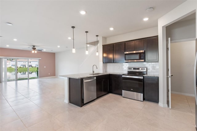 kitchen featuring hanging light fixtures, tasteful backsplash, stainless steel appliances, dark brown cabinets, and sink