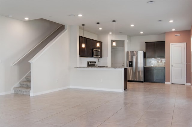 kitchen with dark brown cabinets, kitchen peninsula, hanging light fixtures, stainless steel appliances, and light stone countertops