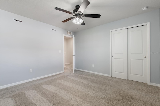 unfurnished bedroom with ceiling fan, light colored carpet, and a closet